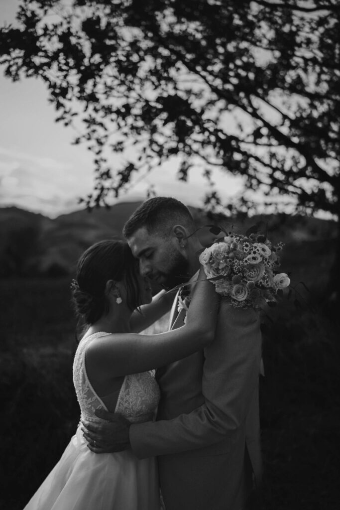 Coppia di sposi abbracciati con un bouquet di fiori.