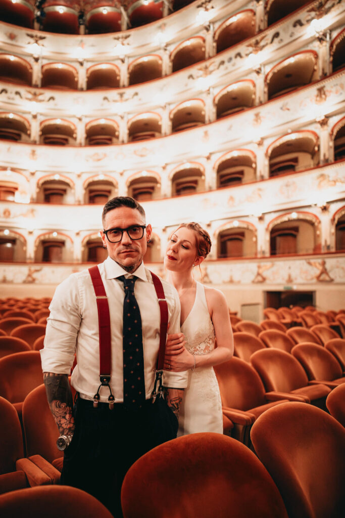 Coppia di sposi in un teatro con posti a sedere in velluto arancione.