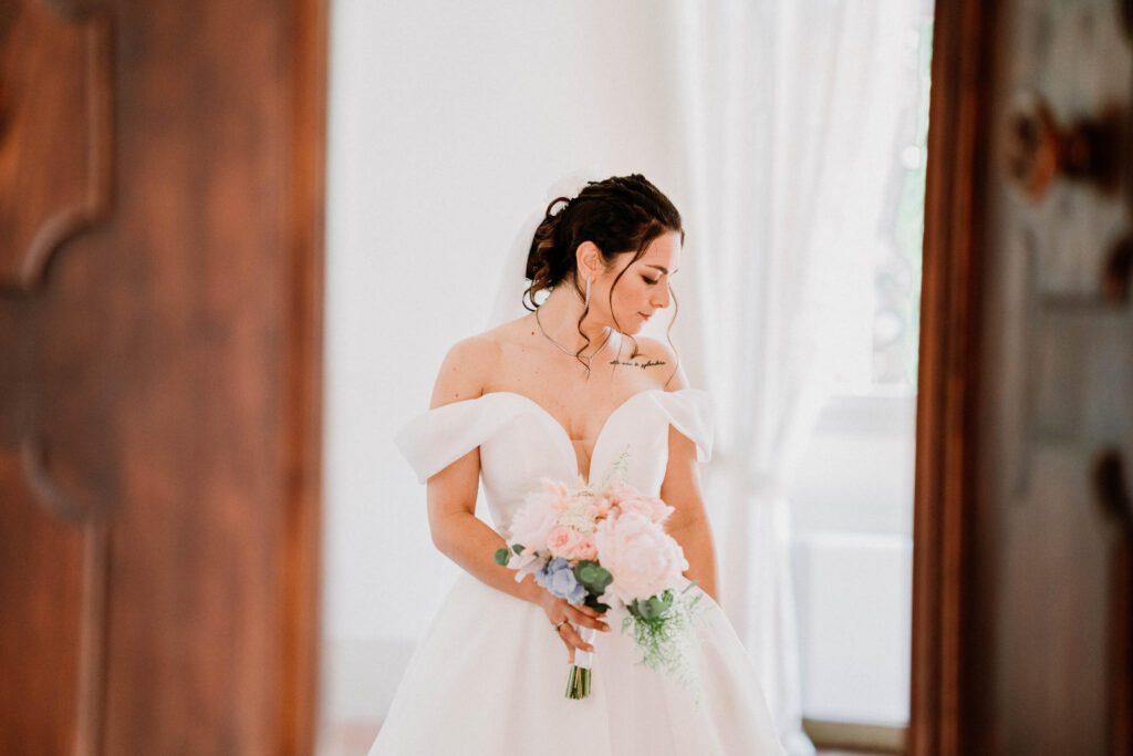 Sposa con bouquet di fiori rosa e blu, abito bianco