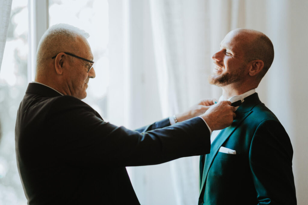 Padre aiuta figlio ad allacciare il papillon per il matrimonio.