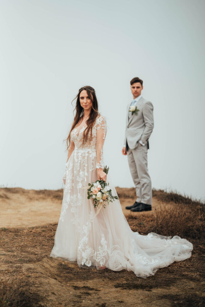 Sposa e sposo all'aperto su un terreno incolto con bouquet.